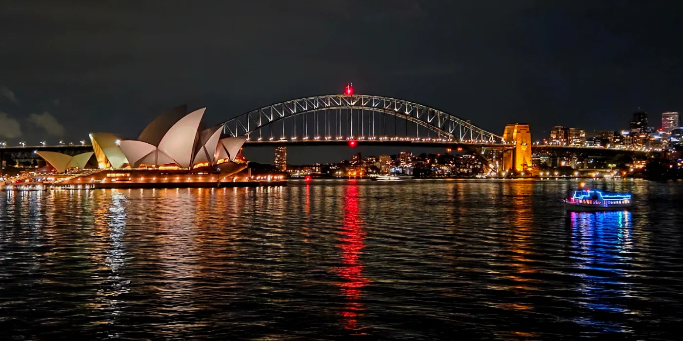 Sydney Harbour at night — the Opera House and Harbour Bridge lit up over the water