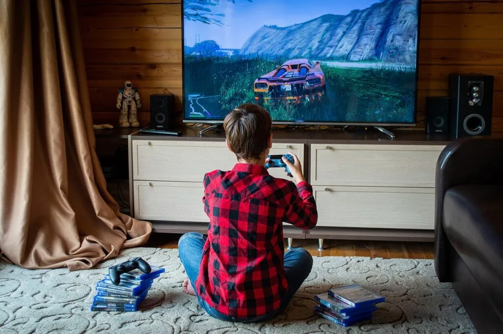 A boy sitting in front of a screen playing a video game at home