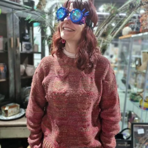 A woman smiling brightly, wearing playful kaleidoscope glasses