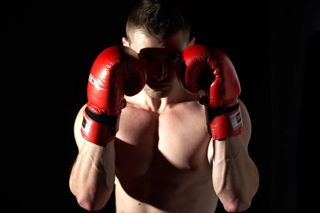 A boxer in a guard stance with red gloves